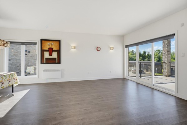 Living room with white walls, wood floors, large windows, and sliding glass doors to a balcony. - 55 Rue Du Britannia, #2, Gatineau
