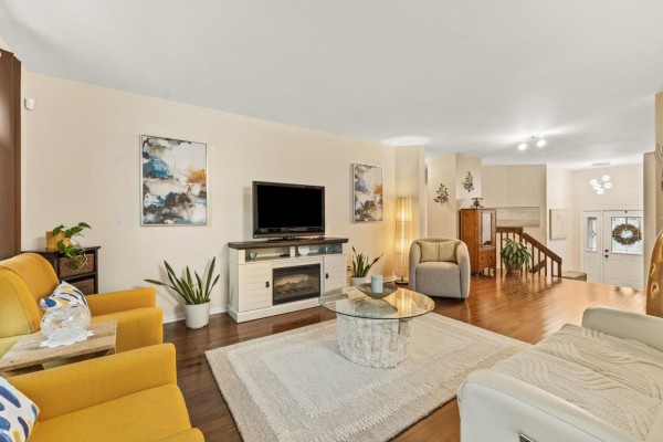 Living room with a fireplace, two yellow armchairs, a white sofa, and hardwood floors. - 55 Rue Du Renard, Gatineau