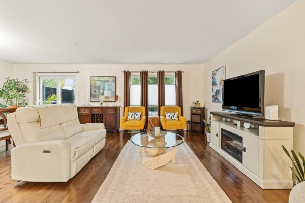 Living room with a white sofa, fireplace TV stand, and two yellow armchairs. - 55 Rue Du Renard, Gatineau