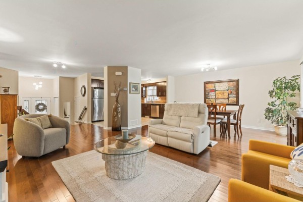 Living room and dining area with hardwood floors, white sofa, and view of the kitchen. - 55 Rue Du Renard, Gatineau