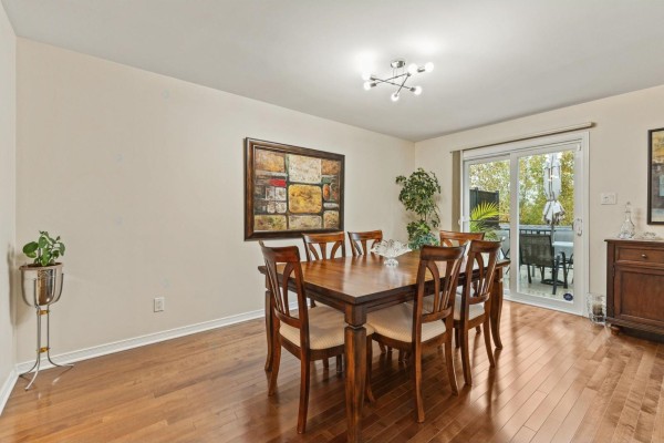 Dining room with a wooden table and chairs, sliding glass doors to a patio, and hardwood floors. - 55 Rue Du Renard, Gatineau