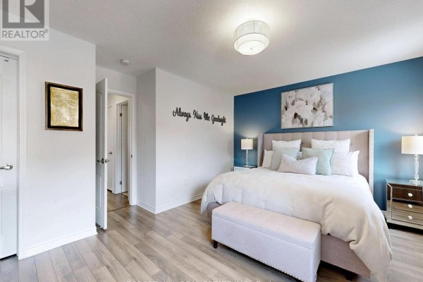Bedroom with king bed, blue accent wall, artwork, and storage bench - 55 Stocks Lane Aurora