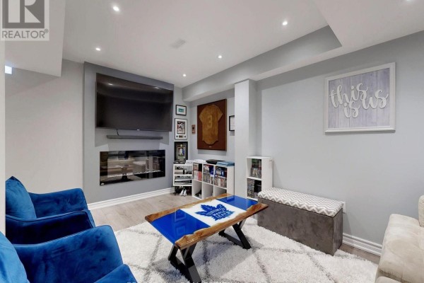 Blue armchairs, fireplace, TV, and Maple Leafs coffee table in living room - 55 Stocks Lane Aurora