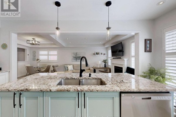 Kitchen island with granite countertops and pendant lights, open to living room - 55 Stocks Lane Aurora