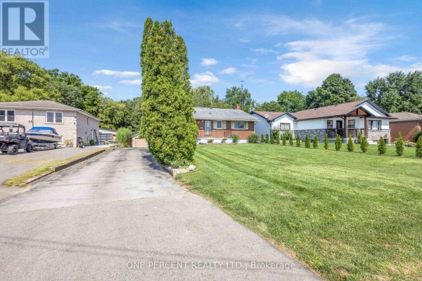 Driveway leading to a single-story red brick house with a manicured lawn and neighboring homes. - 55 Young Street, Tillsonburg