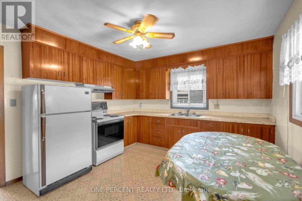 Vintage kitchen with wood cabinets, white appliances, and floral table - 55 Young Street Tillsonburg