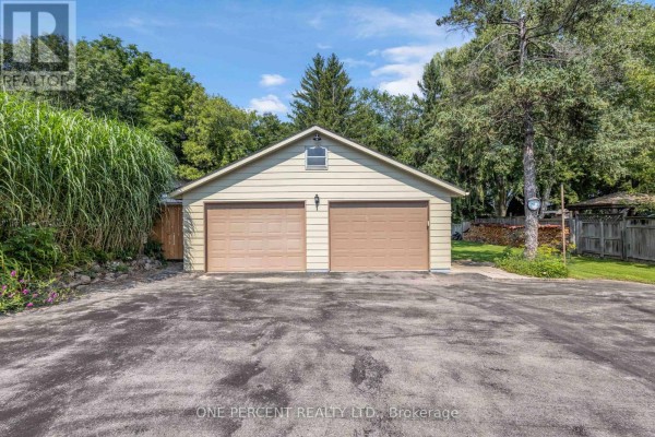 Exterior view of a detached two-car garage with tan doors and a light yellow siding. - 55 Young Street, Tillsonburg