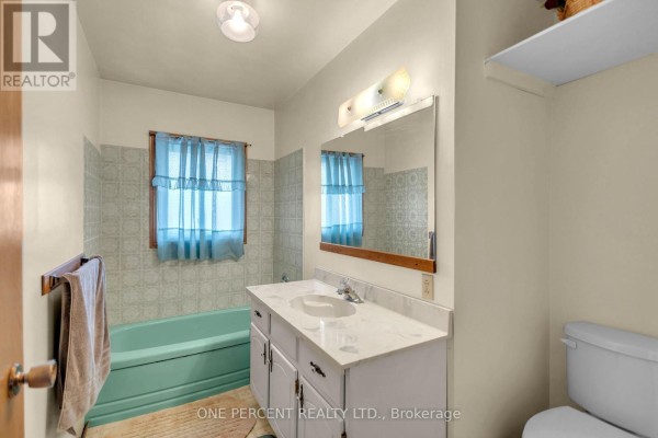 Turquoise bathtub and white vanity with mirror - 55 Young Street Tillsonburg