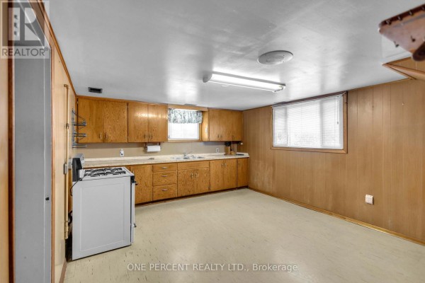 Kitchen with wood cabinets, white stove, and double sink - 55 Young Street Tillsonburg