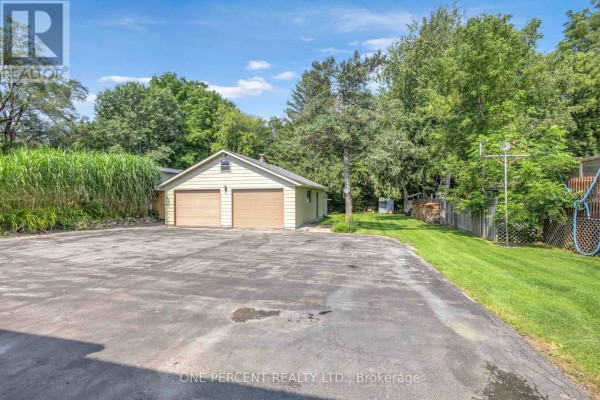 Wide view of a driveway leading to a detached two-car garage and a grassy backyard. - 55 Young Street, Tillsonburg