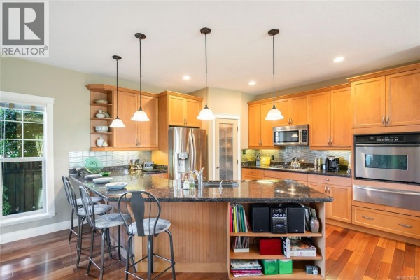 Kitchen island with granite countertop, stainless steel appliances, and pantry door. - 550 Falcon Crt, Parksville