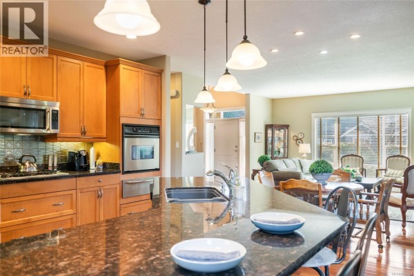 Kitchen island view towards living room with dining table and sofa. - 550 Falcon Crt, Parksville