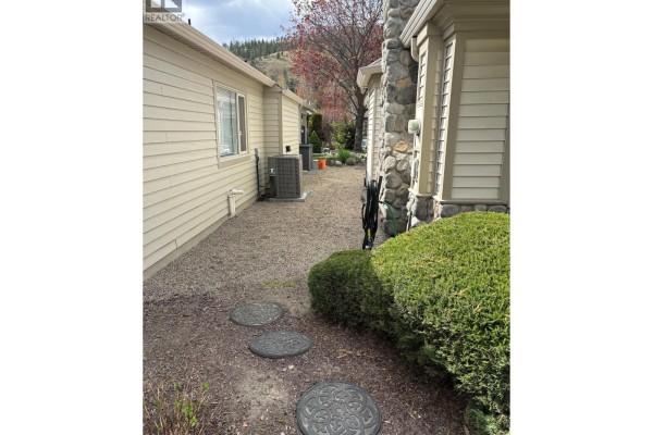 Narrow pathway with decorative concrete circles and gravel beside the house. - 550 Yates Road Unit# 212 Lot# 15, Kelowna