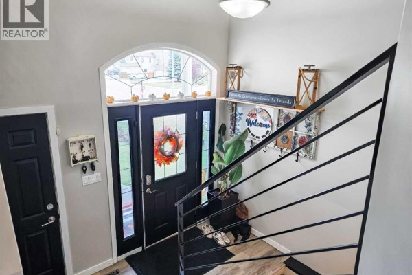 Main entrance foyer with double black doors, an arched transom window, and a carpeted staircase. - 5501 17 Avenue, Edson