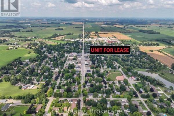 Aerial view looking down a long, straight street lined with houses and businesses in Huron East. - 551 Turnberry Street, Huron East