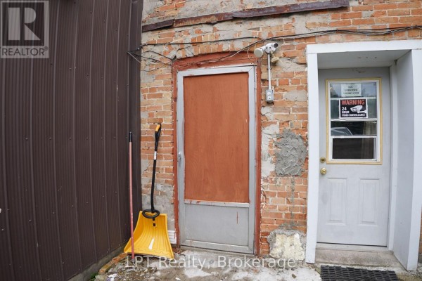 Close-up of two doors on a brick building with a security camera and snow shovel nearby. - 551 Turnberry Street, Huron East