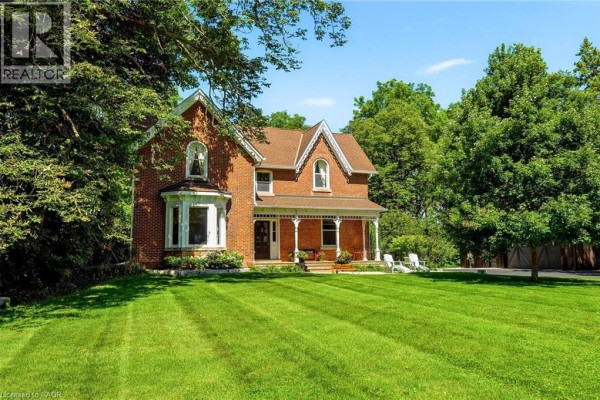 View of a large, manicured lawn behind the house, bordered by mature trees and a wooden fence. - 5515 Blind Line, Burlington