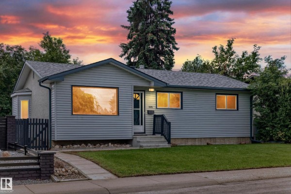 Exterior view of a light blue vinyl-sided bungalow at sunset with illuminated windows and a dark sky. - 5519 142 Av Nw Nw, Edmonton