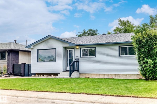 Side view of a light blue vinyl-sided bungalow with a well-kept lawn and mature trees. - 5519 142 Av Nw Nw, Edmonton