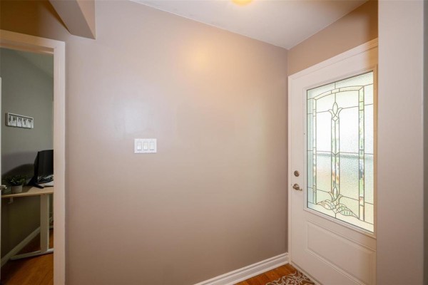 Interior view of the entrance hall with a white front door featuring stained glass. - 552 Ravelston Avenue W, Winnipeg