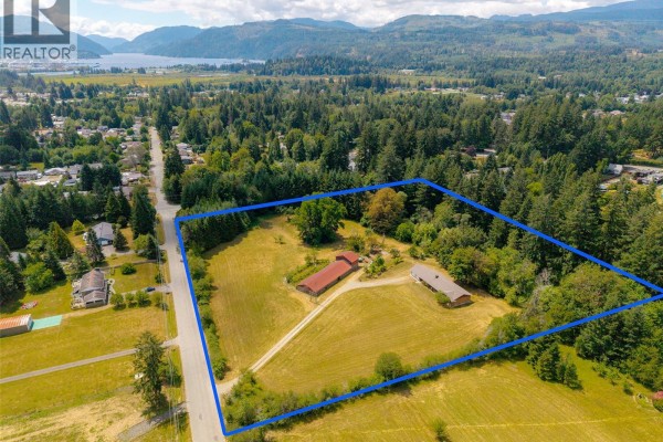Aerial view of the 5526 Grandview Rd property, Port Alberni, with clearings, trees, and surrounding residential area. - 5526 Grandview Rd, Port Alberni