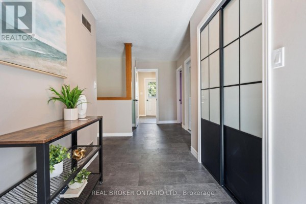 Hallway of a home with dark tile flooring, a console table, and glass-paneled closet doors. - 553 Norfolk County Road 21, Norfolk