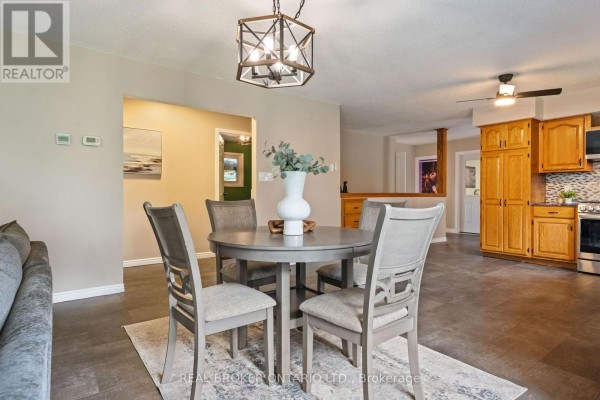 Dining area with a round table and chairs, adjacent to a kitchen with wooden cabinets. - 553 Norfolk County Road 21, Norfolk