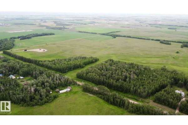 Aerial view of a wide rural landscape with fields, scattered trees, a small cluster of homes, and buildings. - 553-lot C Range Road 201, Rural Lamont County