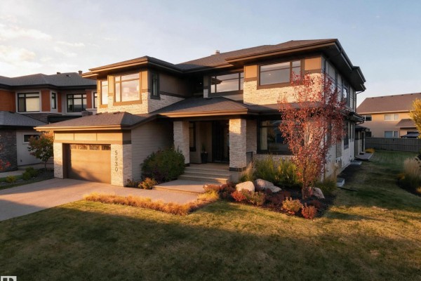 Home office with built-in shelving, a large round table, a patterned rug, a plush sofa, and an adjacent foyer. - 5530 Chegwin Pt Sw, Edmonton