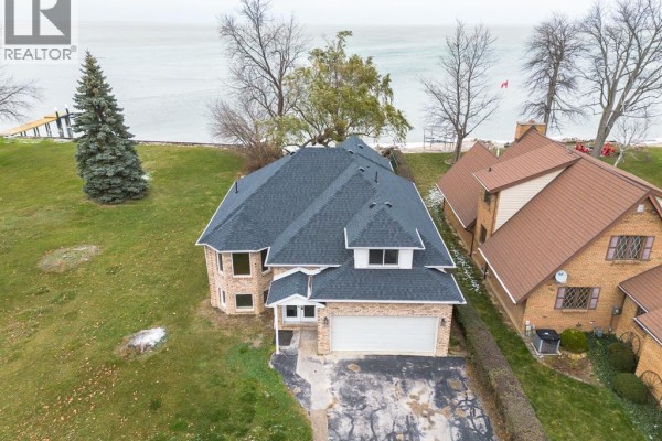 Aerial view of a large house with a dark roof and brick exterior beside the water. - 5530 St. Clair, Lakeshore