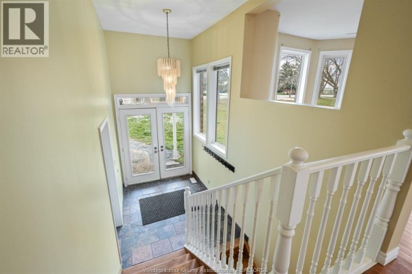 Interior view of a foyer with a staircase, light yellow walls, and a chandelier. - 5530 St. Clair, Lakeshore