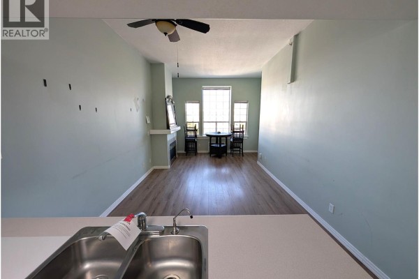 View from kitchen to living room showing a fireplace, dining table, and large windows. - 554 Seymour Street Unit# 411, Kamloops