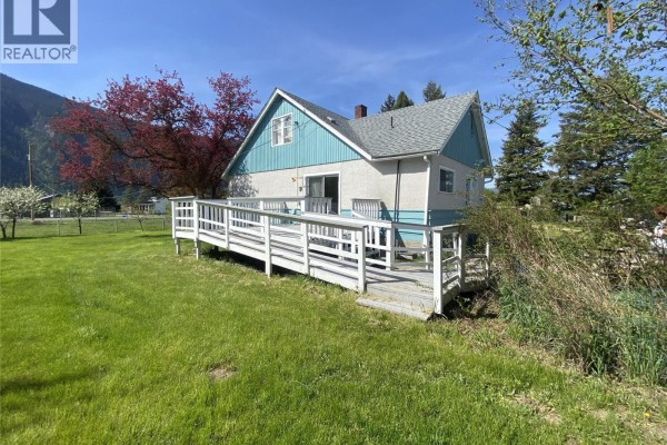 Rear view of the house with a white ramp leading to a door and a large deck with white railings. - 555 Carson Road, Grand Forks