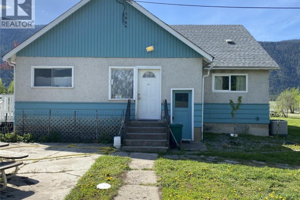 Front exterior of a house with light grey stucco and blue siding, a white door, and steps. - 555 Carson Road, Grand Forks