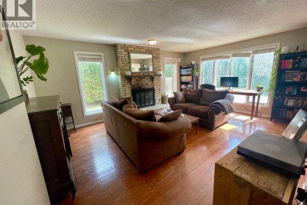 Cozy living room featuring a brick fireplace, comfortable seating, large windows, and a built-in bookshelf. - 555 Jeffreybrook Drive, London