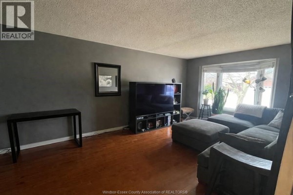 Family room with a large sectional sofa, entertainment unit, bay window, and dark gray accent wall. - 555 Jeffreybrook Drive, London