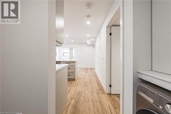 Hallway inside the apartment looking towards the kitchen area and a laundry machine. - 555 Sanatorium Road Unit# 101, Hamilton
