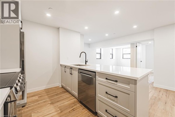Modern kitchen with light grey cabinets, white quartz countertops, and stainless steel appliances. - 555 Sanatorium Road Unit# 101, Hamilton