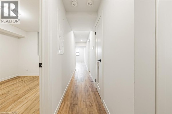 Interior hallway with white walls, light wood floors, and doors leading to rooms. - 555 Sanatorium Road Unit# 102, Hamilton