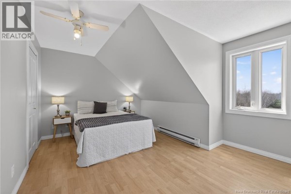 Finished basement with dark wood floor, white trim, and view of staircase and living area. - 5551 Route 11, Riviere Du Portage