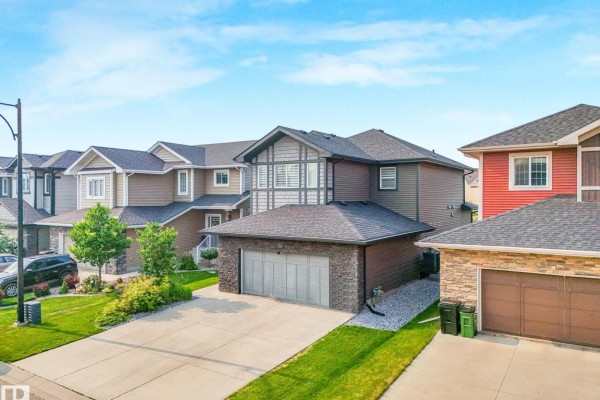 Aerial view of a house with a three-car garage and grey siding, surrounded by similar homes. - 556 Merlin Ld Nw, Edmonton