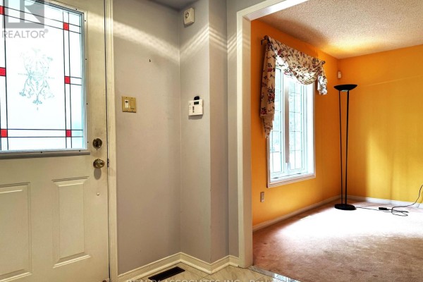 View from the entrance foyer looking into a living room with orange walls. - 5577 Haddon Hall Road, Mississauga
