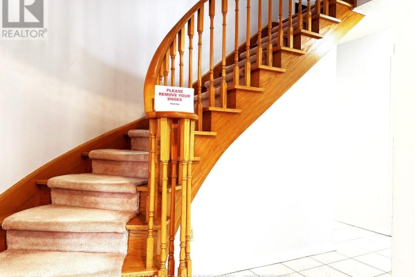 Curving wooden staircase with carpeted steps and white spindles. - 5577 Haddon Hall Road, Mississauga