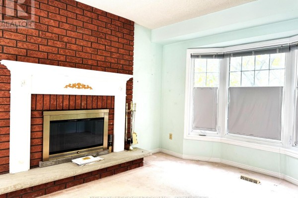 Living room with a brick fireplace, white mantel, and a bay window. - 5577 Haddon Hall Road, Mississauga