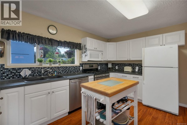 Bedroom with a large bed, rocking chair, wooden floors, and large windows. - 558 Alder St, Campbell River