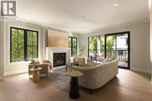 Living room with a gas fireplace, plush sofa, armchairs, large windows, and sliding glass doors to a balcony. - 5593 Mackenzie Street, Vancouver