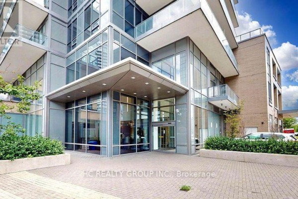 Entrance to a modern condo building with glass facade and landscaping. - 56 Forest Manor Road, Toronto