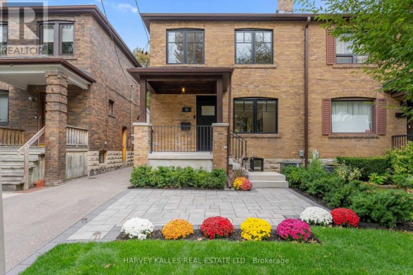 Front facade of a brick semi-detached home with dark-framed windows and a covered entrance. - 56 Glengarry Avenue, Toronto