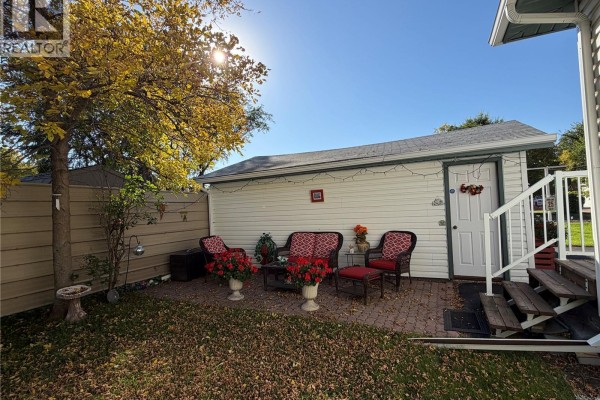 Backyard view of the house, showing a driveway, a detached garage, and a shed. - 56 Haultain Avenue, Yorkton