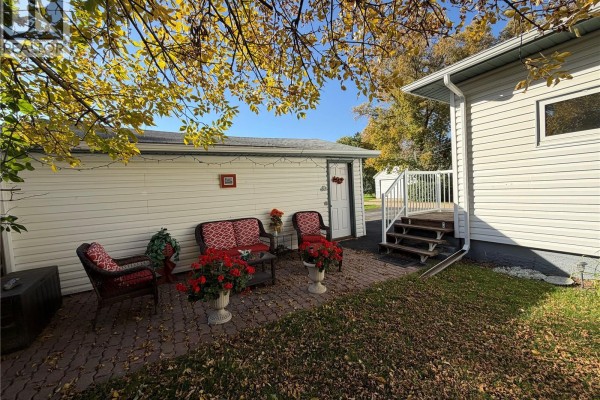 Rear view of the house and outbuildings with a driveway and lawn. - 56 Haultain Avenue, Yorkton